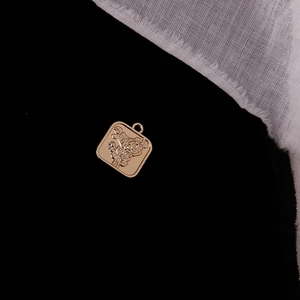 Detail of square gold alloy pendant featuring intricate rose floral embossing with link ring