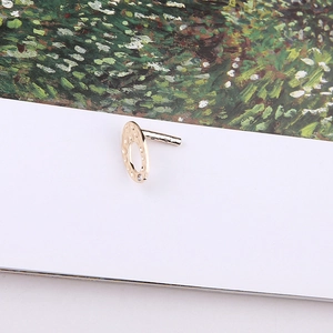 Detail of gold hammered round stud earring with small crystal stone on white card