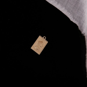 Macro shot of rectangular gold coin pendant featuring Elizabeth II portrait on black background