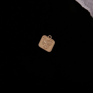 Macro detail of square gold alloy flower pendant with relief design on black background