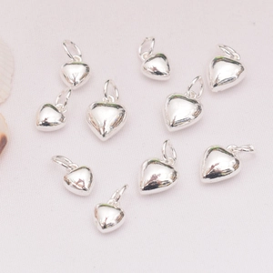 Polished 14K gold-filled solid heart pendants set of nine on white textured fabric background