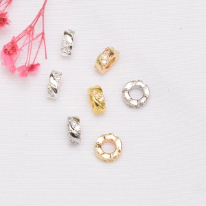 Detalle macro de cuentas espaciadoras bañadas en oro 14K con textura de cuerda y circonita