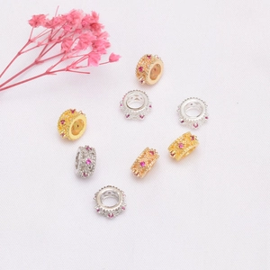Dettaglio macro di perline distanziatrici placcate oro 14K con zirconi rosa per gioielli fai da te