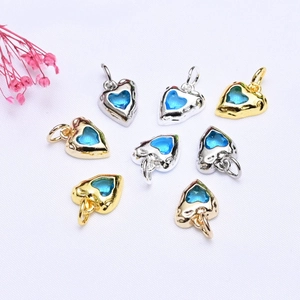 Close-up of 14K gold and silver heart pendants with blue zircon for DIY necklace jewelry