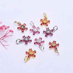 Macro detail of 14K gold filled flower charms with pink zircon petals and silver plating
