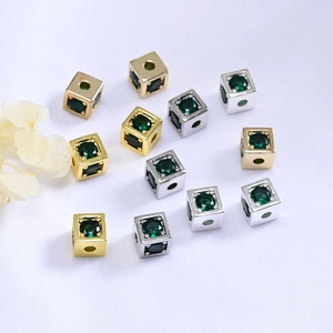 Detalle macro de cuentas cuadradas bañadas en oro de 14K con circonitas verdes para bricolaje