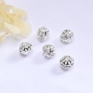 Macro shot of silver hollow cubic zirconia beads on a white silk background for jewelry DIY