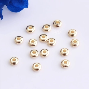 Cuentas rondelle pulidas bañadas en oro de 14K sobre fondo blanco con flores azules