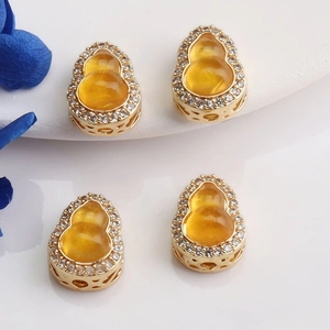 Detailed view of 14K gold gourd charms with orange inlay and zircon pave borders