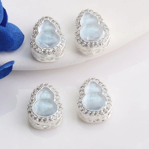 Detailed view of hollow filigree 14K gold wulu pendants with blue stones and white zircons