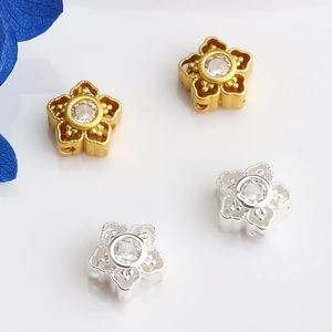 Macro detail of flower-shaped charms with hollow petals and inset cubic zirconia stones