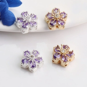 Macro view of 14K gold plated flower charms with purple zircon stones for jewelry making