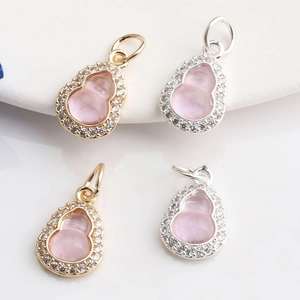 Macro view of 14K gold gourd charms with pink gemstones and pavé zircon detailing
