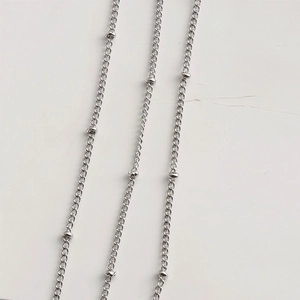 Macro shot of silver beaded chain links featuring smooth metal accents and polished oval rings