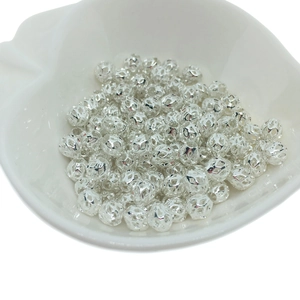 Silver hollow filigree metal beads in a shell dish for DIY jewelry making