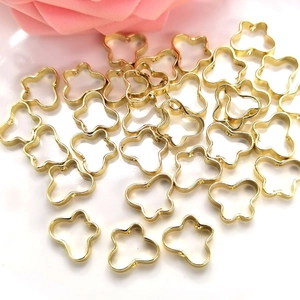 Golden flower hollow beads frames for DIY jewelry making displayed on a white surface