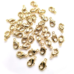 Macro view of scattered 14k gold-filled lobster clasps for DIY jewelry making