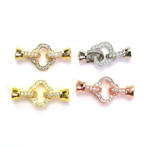 Close-up of four-leaf clover jewelry clasps in gold and silver with micro-pave zircons