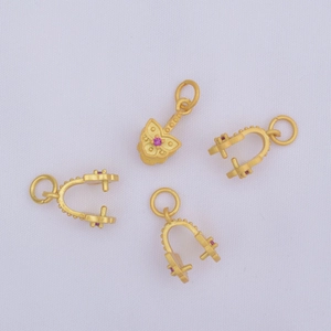 Detalle de colgante de mariposa en oro mate y cierres en U con piedras preciosas moradas