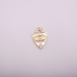 Macro detail of 14K gold evil eye charm with teardrop zircon and pave set stones