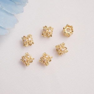 Dettaglio macro di perle distanziatrici a fiore cavo placcate oro 14K con zirconi lucidi