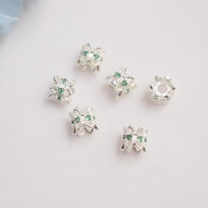 Dettaglio di distanziatori in argento placcato oro 14K con zirconi verdi su tessuto