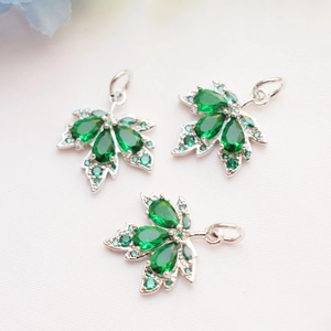 Detailed view of silver maple leaf pendants featuring green pear-shaped zircon stones
