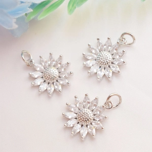 Macro detail of three silver sunflower pendants with inlaid marquise-cut cubic zirconia