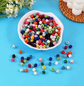 Colorful acrylic barrel beads in a white shell bowl for DIY jewelry and crafts