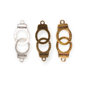 Detailed view of alloy handcuff pendants in silver, bronze, and gold with FREEDOM engraving