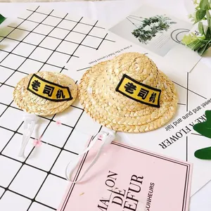Detail of woven straw pet hat featuring personalized embroidery and adjustable white strap
