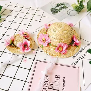 Detail of woven straw pet hats with pink floral decorations and elegant lace ribbons