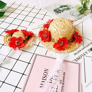 Close-up of pet straw hats with red fabric flowers and white lace ribbon ties