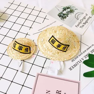 Detail of mini woven pet straw hats with adjustable straps and yellow patch embroidery