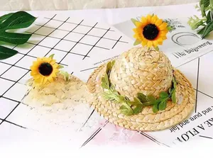 Macro detail of handmade pet straw hats featuring decorative sunflowers and green leaves