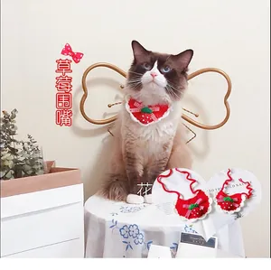 Detail of red handmade crochet strawberry pet bib with white lace and checkered bow
