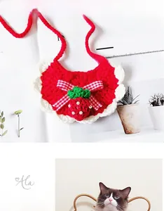 Detailed view of hand-knitted strawberry pet bib with red bow and pearl accents