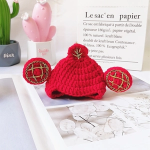 Dettaglio di cappello rosso all'uncinetto per animali con ricami dorati e finiture a mano