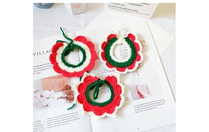 Detail of handmade red and green crochet pet collar with flower pattern on a magazine