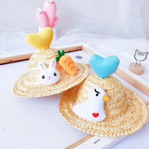 Detail of straw pet hats with knitted hearts and plush rabbit or goose decorations