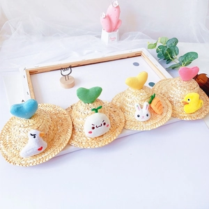 Detail of four mini pet straw hats with colorful knit hearts and cute plush characters