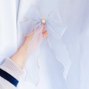 Close-up of light blue organza lace bow collar with white pearl and gold stitching