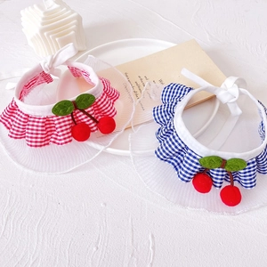 Detail of red and blue checkered pet bibs with mesh lace and cherry accents on white cloth