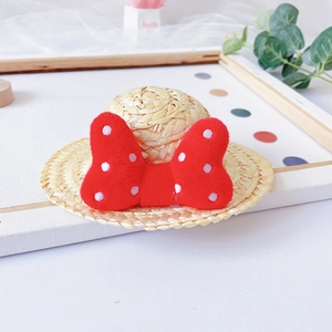 Detailed view of mini straw pet hat featuring a red polka dot bow decoration