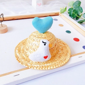 Close-up of a mini straw pet hat with a blue plush heart and cute white duckling decoration