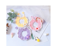 Detailed macro view of hand-knitted pet bibs with decorative crochet flowers and ties
