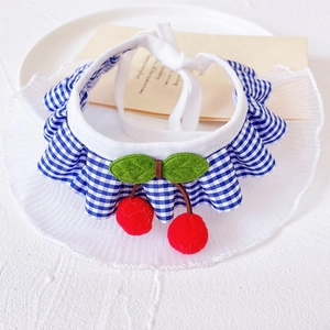 Detail of blue plaid pet bib with white lace trim and 3D plush cherry decoration