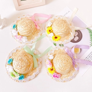 Detail of pet straw hats with lace edges, vibrant flowers, and silk adjustable ribbons