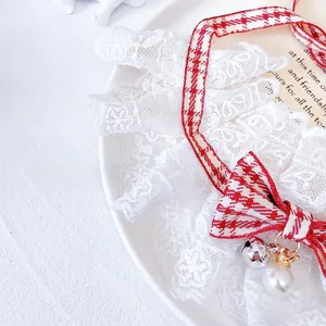 Detailed view of plaid pet collar with layered lace, silver bell and crown charm