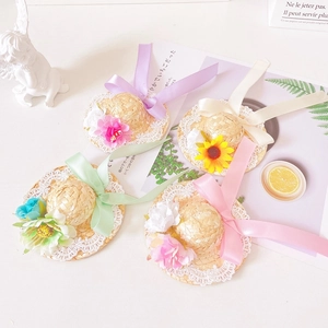 Flat lay of mini pet straw hats with lace edges and colorful floral ribbon decorations